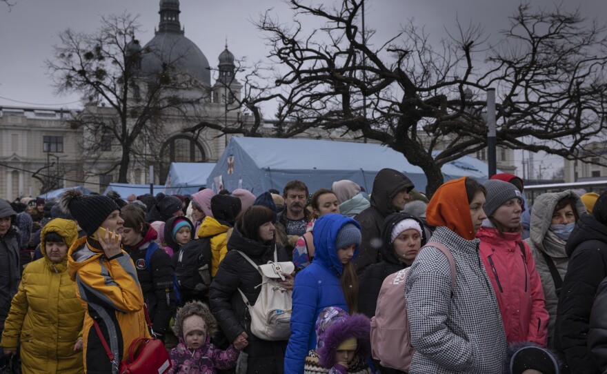 Families wait to make their way from the main bus and train terminal on Saturday in Lviv, Ukraine. More than 1 million people have fled Ukraine following Russia's assault on the country, with many Ukrainians passing through Lviv on their way to Poland.