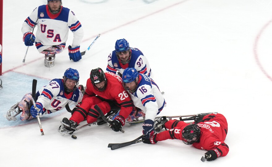Team USA's Declan Farmer, center, fights for the puck during the gold-medal match against Canada.