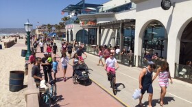Pedestrians and bicyclists take in the sights and sounds of the Mission Beach boardwalk, May 1, 2016.