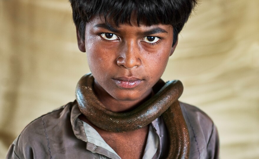 Vijay Nath, 12 exhibits his harmless sand boa. His family stays on the lookout for police: Snake handling has been outlawed since 1972. Gujarat, India, 2009.