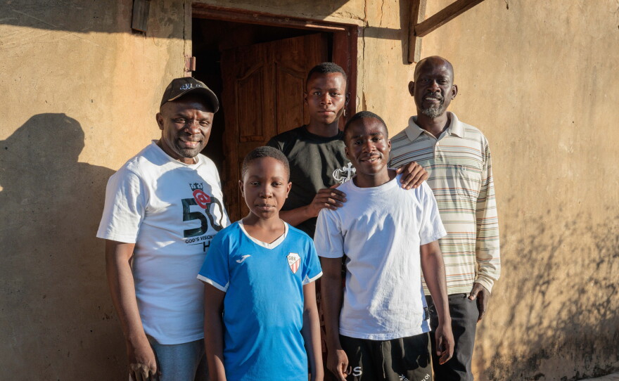 The boys pose for a picture with Pastor Billy (left) and their Uncle John (right) outside their home.