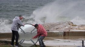 John Garrisi, left, and Gaige Graf move an outdoor table away from the shorefront during the early stages of a nor'easter storm on Friday.