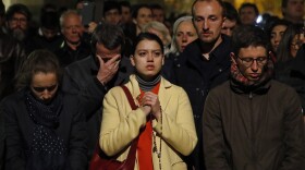 People pray as Notre Dame cathedral burns in Paris, Monday, April 15, 2019. 