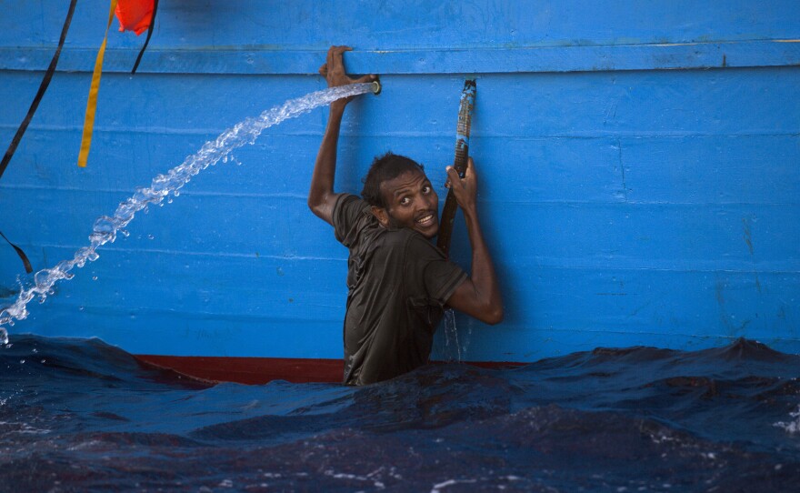 A man clutches the side of a boat after jumping into the sea during a rescue operation in the Mediterranean, about 13 miles north of Sabratha, Libya.