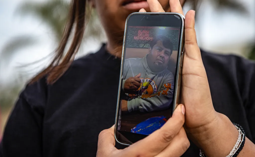 Mia Ortiz holds a photo of her father on her phone while talking to reporters on July 11, 2025. Mia Ortiz said she hasn’t heard from her father, Rafael Ortiz, since she heard about the immigration raid at Glasshouse Farms just a day prior on July 10.