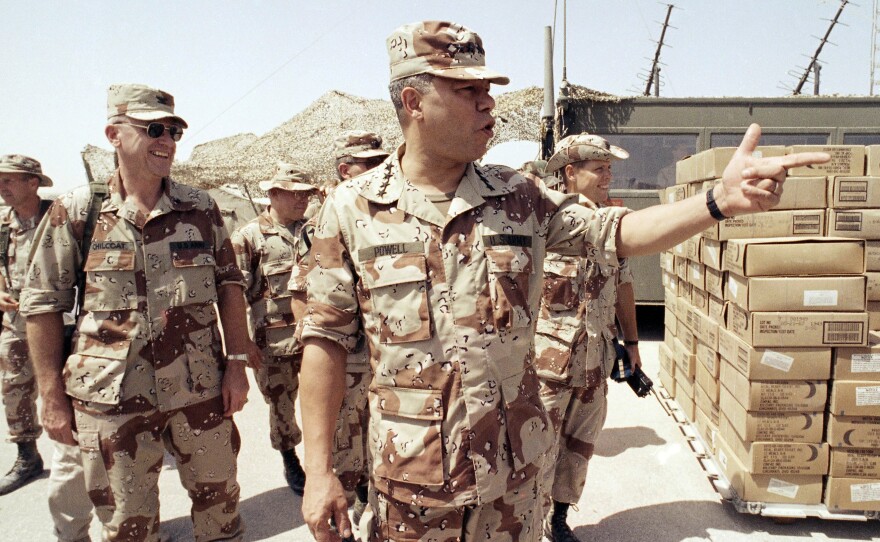 Gen. Colin Powell, chairman of the Joint Chiefs of Staff, points to a group of American troops at an airbase after his arrival in Saudi Arabia on Sept. 13, 1990. Powell served as chairman under both Presidents George H.W. Bush and Bill Clinton.