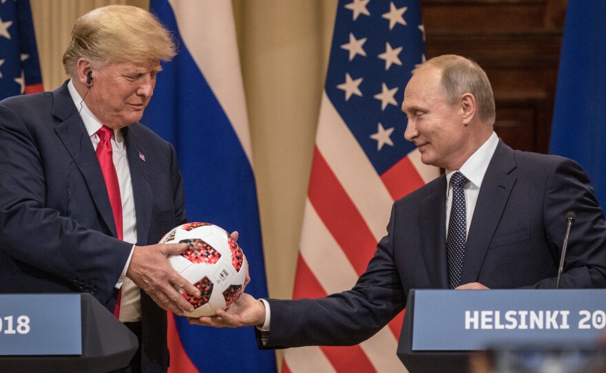 Russian President Vladimir Putin hands President Trump a World Cup soccer ball during a joint news conference after their summit on Monday in Helsinki.