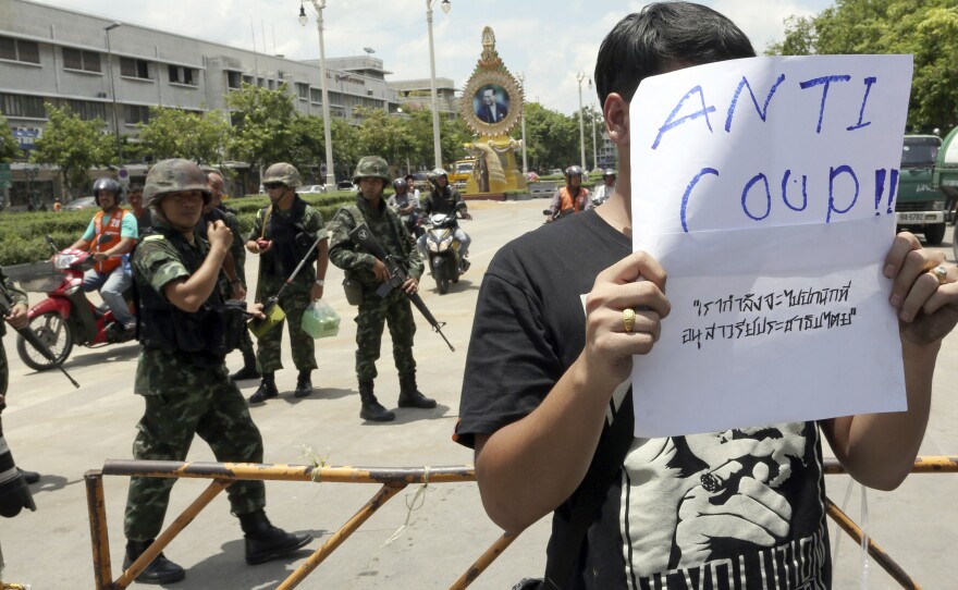 A Thai student holds an anti-coup sign in front of a group of soldiers during a brief protest near the Democracy Monument in Bangkok on Friday.