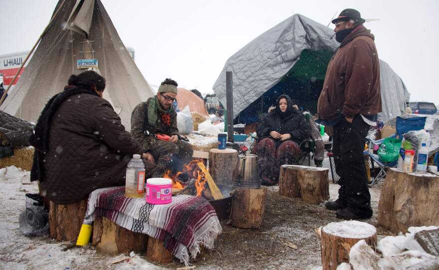 Protesters sit around a campfire as it snows at Oceti Sakowin camp on Monday.