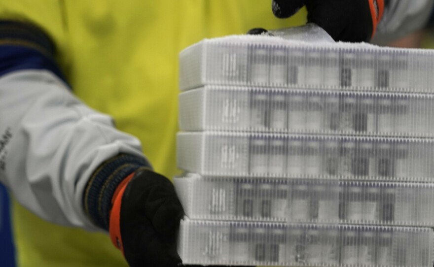 A worker carries boxes containing the Pfizer-BioNTech COVID-19 vaccine that were being prepared for shipment from a Pfizer facility in Portage, Mich., in December.