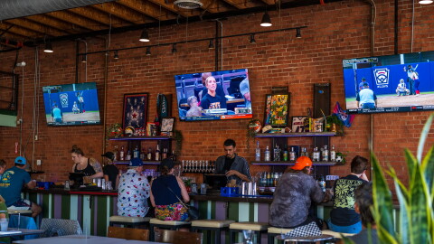 Customers sitting at the bar watch women's basketball and softball at One of Us in North Park on July 22, 2026. One of Us is San Diego's first women's sports bar.
