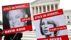 Members of the American Federation of Teachers hold up signs depicting Education Secretary Betsy DeVos and Koch brother, David Koch, while protesting in support of unions outside of the Supreme Court in Washington, Feb. 26, 2018. 