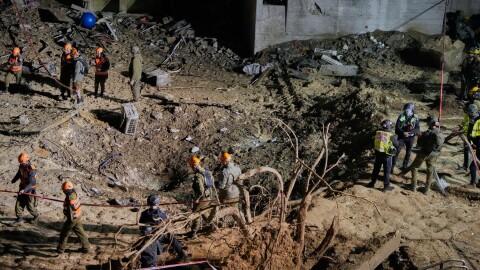 Israeli security forces and rescue teams inspect the crater left by an Iranian missile in Arad, southern Israel, Sunday, March 22, 2026.