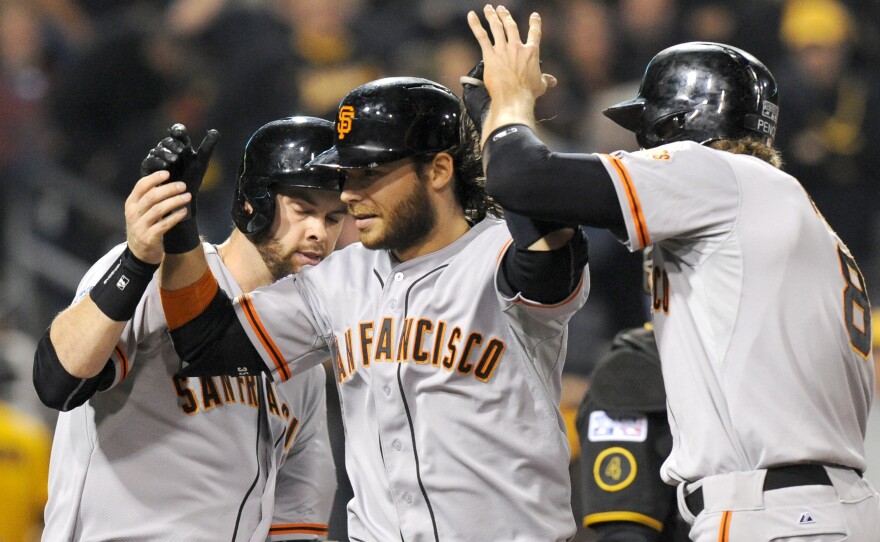 San Francisco Giants' Brandon Crawford, center, is greeted by teammates Brandon Belt, left, and Hunter Pence right, after hitting a grand slam against the Pittsburgh Pirates.
