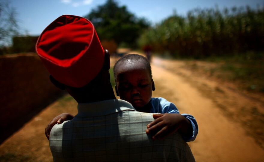 Ado Ibrahim carries his son Aminu through a village in northern Nigeria. Aminu was paralyzed by polio.