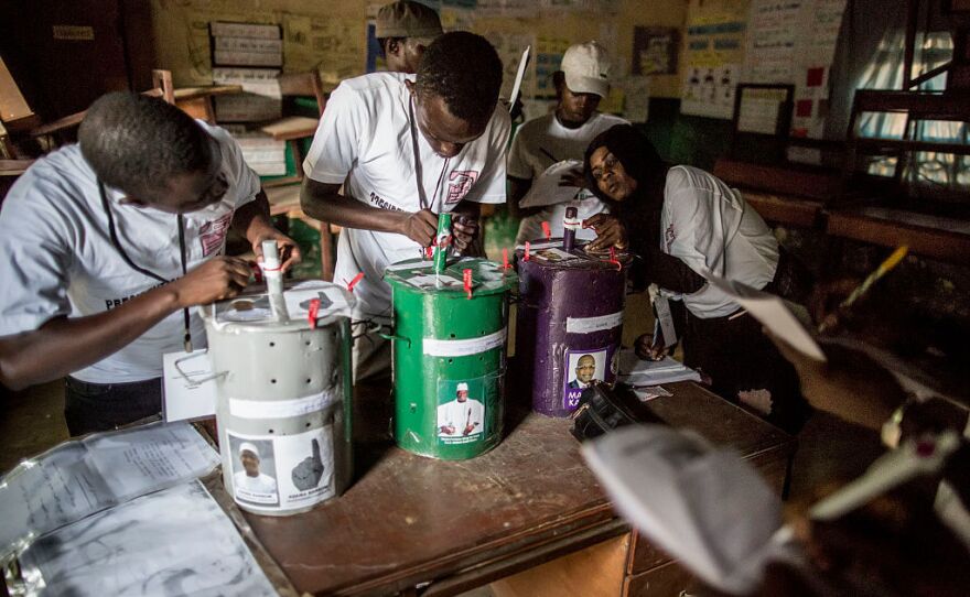 Polling officials check the seals on the voting drums Friday at a polling station in Banjul.