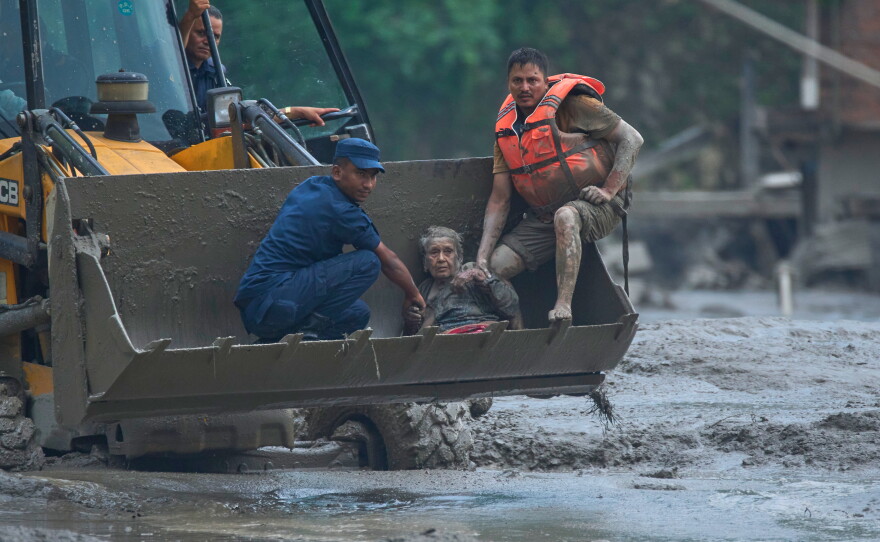 Rescuers use an earthmover to carry a victim of flash flooding to safety along the Trishuli River in Nepal's Nuwakot district, Wednesday, Aug. 26, 2026.
