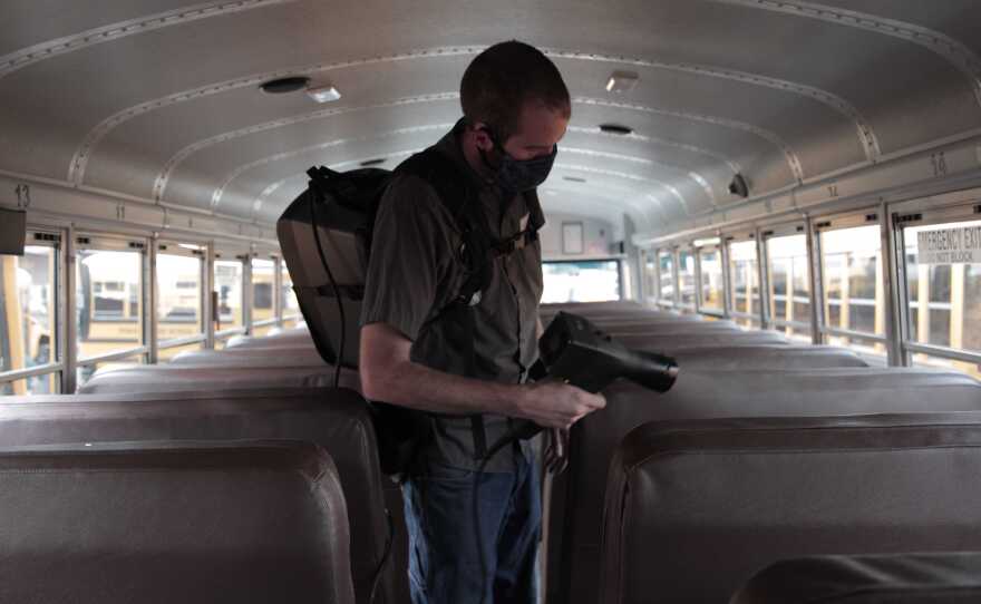 Tyler Bouquet, a vehicle maintenance coordinator at Poway Unified School Districts, disinfects a school bus with a machine that produces an electrostatic fog. Nov. 5, 2020