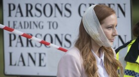 An injured woman is assisted by a police officer close to Parsons Green station in west London after an explosion on a packed London Underground train, Friday, Sept. 15, 2017.