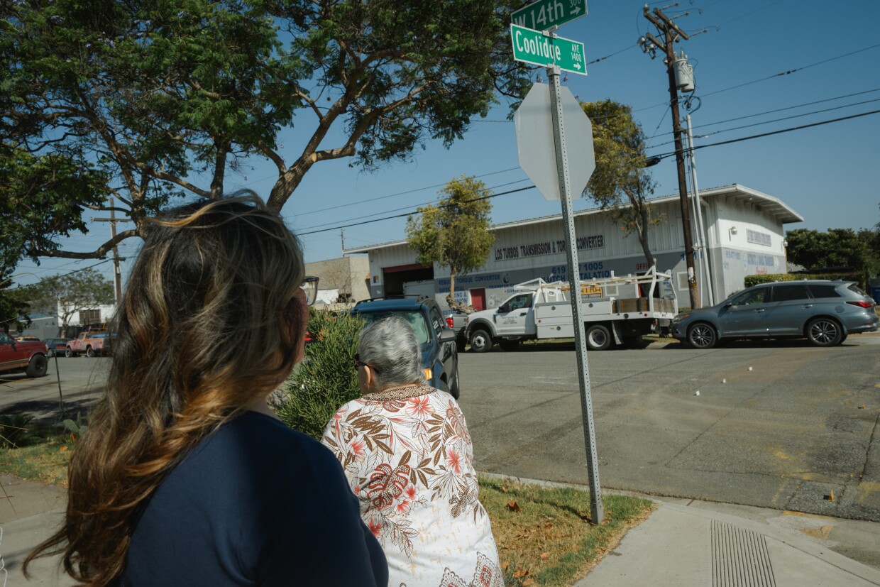 Margarita Garcia and her daughter, Maggie Morales, walk across the street from an auto body shop near Garcia’s home in the Old Town neighborhood of National City, California on June 27, 2025. Garcia has worked with the Environmental Health Coalition to push back against pollution in her neighborhood for decades.