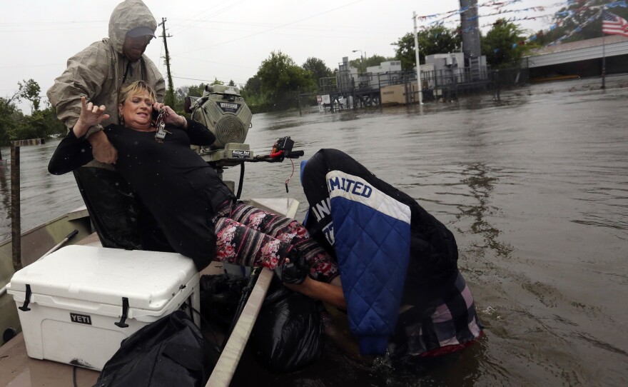 Rhonda Worthington is lifted into a boat while on her cellphone with a 911 dispatcher on Monday in Houston. Houston and other areas along the Gulf Coast are facing intense flooding from Tropical Storm Harvey.