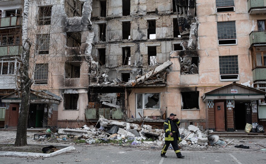 <strong>April 20:</strong> A rescue worker walks past a heavily damaged apartment building in Hostomel, Ukraine. Russian forces occupied Hostomel for weeks as part of their failed attempt to seize Kyiv. Their retreat revealed the scale of devastation in Hostomel and other towns outside the capital city.