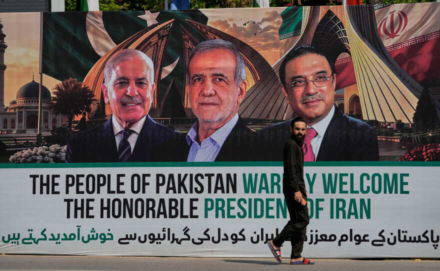 A man walks past a welcoming billboard featuring Iranian President Masoud Pezeshkian, center, with Pakistan President Asif Ali Zardari, right, and Shehbaz Sharif along a roadside in Islamabad, Pakistan, Tuesday, June 23, 2026.