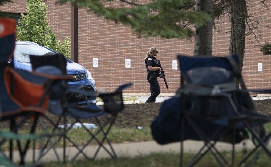 An armed law enforcement officer patrols the scene of the Fourth of July parade shooting in Highland Park.