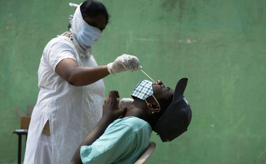 A health worker collects a nasal swab sample from a man to test for the coronavirus in Hyderabad. Tests are in short supply in India, where the Health Ministry confirmed 386,453 infections Friday — more than any country on any day since the pandemic began.