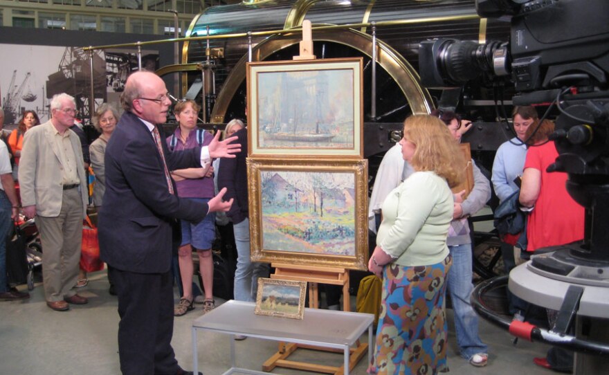 Paintings specialist Dendy Easton examines two pictures.