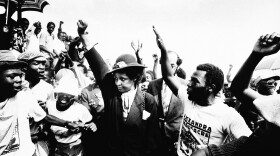 Winnie Mandela raises her fist during the funeral for 17 people who were killed during fierce rioting on Wed. March 5, 1986 in Johannesburg's Alexandra township.