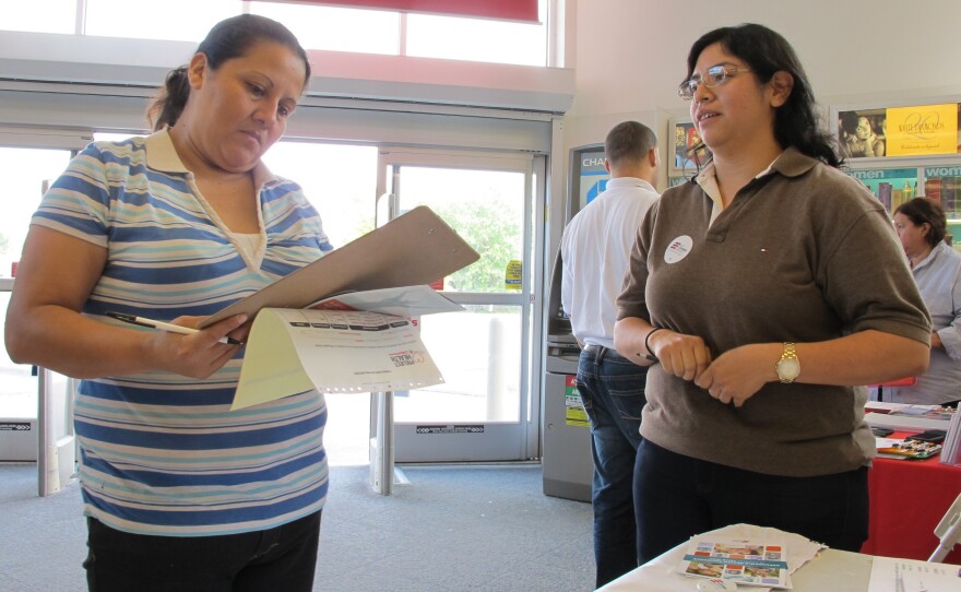 Enroll America outreach worker Rosy Mota (right) talks about the federal health care law with a CVS customer.