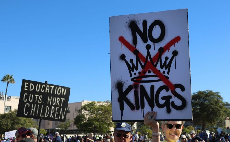 Protesters hold up signs during a demonstration for a 'No Kings' rally in San Diego on Oct. 18, 2025. 