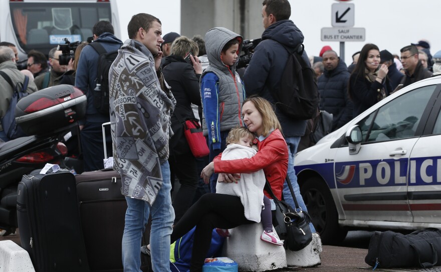 Travelers wait outside the Orly airport, south of Paris, Saturday, March, 18, 2017.
