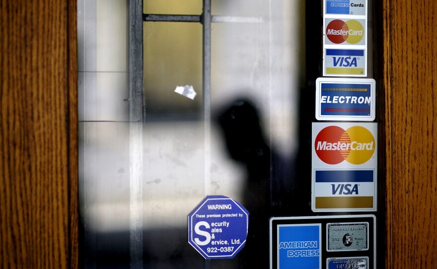 Credit card logos are seen on a downtown storefront as a pedestrian passes in Atlanta in 2012.