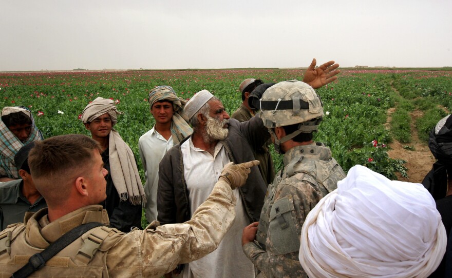 An opium farmer shows damaged poppies to U.S. Marines and their interpreter near Qalanderabad in southwest Afghanistan in 2009.