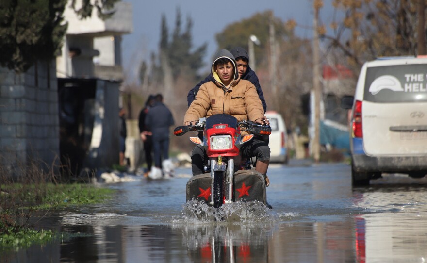 People ride a motorcycle in a flooded area after the collapse of a dam on the Orontes or Assi river near al-Tulul village in Salqin, in Syria's rebel-held Idlib province.