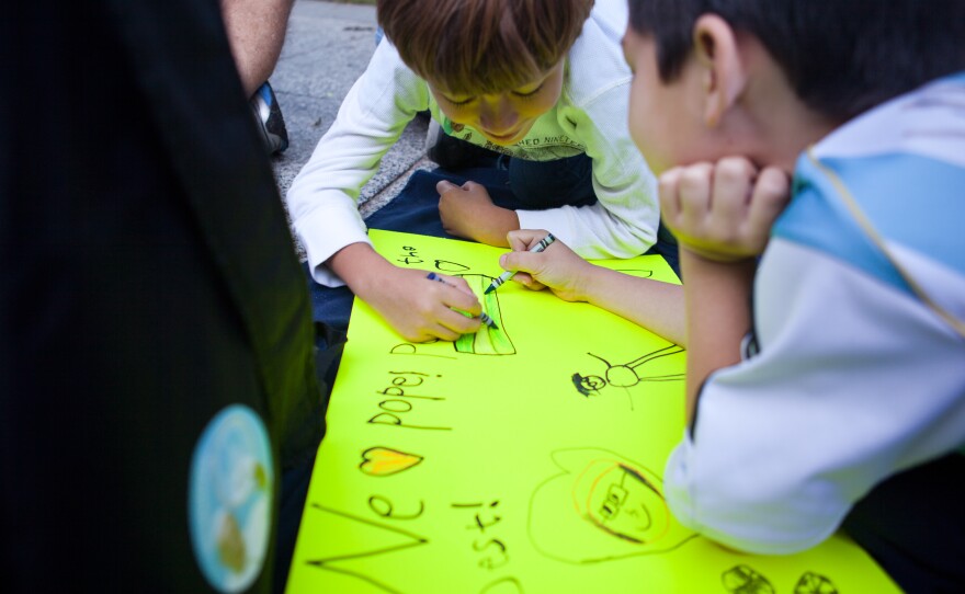 Seven-year-olds Lucas Jefferson (center) and Rafael Xeleya draw on a poster for Pope Francis while waiting for the parade to start.