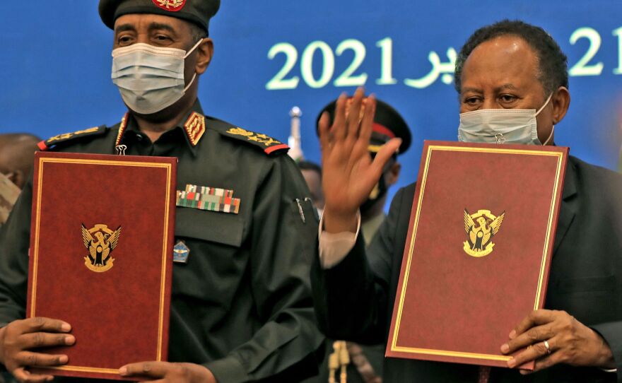 Sudan's top general Abdel Fattah al-Burhan (left) and Prime Minister Abdalla Hamdok lift documents during a deal-signing ceremony to restore the transition to civilian rule in the country in the capital Khartoum, on November 21, 2021.