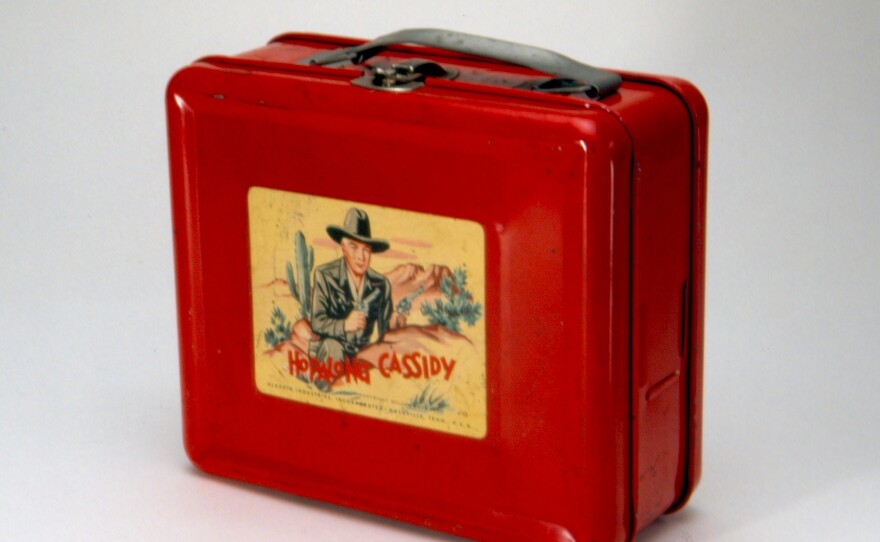 This steel lunch box, made by Aladdin Industries in 1950, was the first to bear a licensed image, and helped Aladdin launch a new product line that would last for decades. Hopalong Cassidy was a popular TV, radio and comic series.
