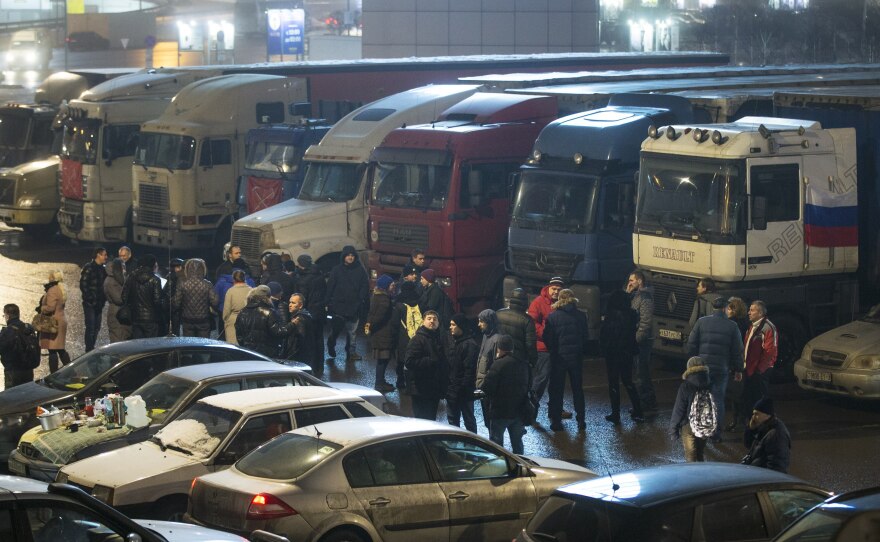Truck drivers protesting new fees walk with supporters among parked trucks outside Moscow on Dec. 4.