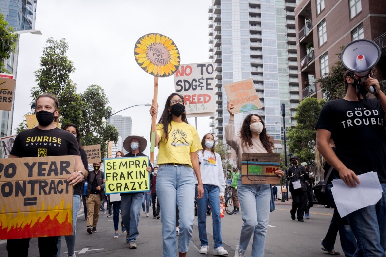 Climate advocates march with signs outside the downtown San Diego headquarters of Sempra Energy on May 14, 2021.