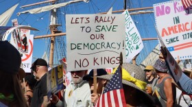 Protestors hold signs during a "No Kings" march on Harbor Drive in San Diego on Saturday, Oct. 18, 2025.