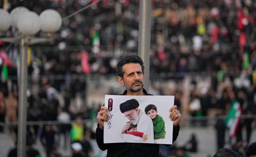 A man holds a picture of slain Iranian Supreme Leader Ayatollah Ali Khamenei as a crowd waits for his casket to arrive at the Imam Khomeini Mosalla Grand Mosque for the start of the dayslong funeral ceremonies in Tehran, Iran, Saturday, July 4, 2026.