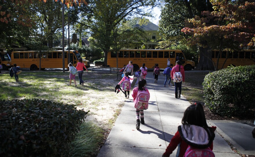 The end of the day at Watts feels like a party in front of the school. Some students rush to board buses while parents and teachers mingle.