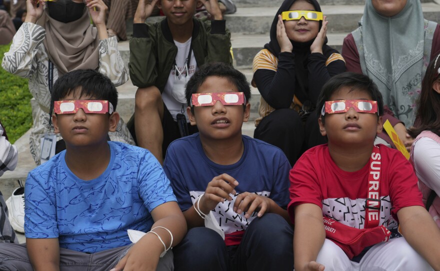 Indonesian youths wear protective glasses to watch solar eclipse in Jakarta, Indonesia, Thursday, April 20, 2023.