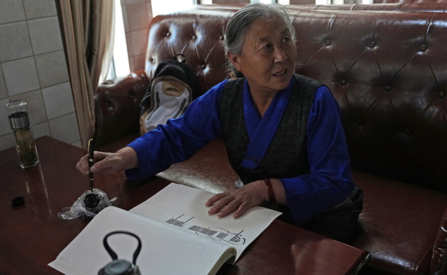 Kalsang Lhamo, a 73-year-old retired nurse, practices Tibetan calligraphy at the Chengguan District Day Care Center for the Elderly in western China's Tibet autonomous region on July 20, 2026, during a government-organized visit for foreign journalists.
