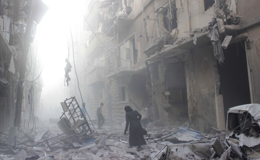 A Syrian woman makes her way through debris following a air strike by government forces in the northern city of Aleppo on Tuesday. Government forces have the momentum and are pushing to drive the rebels out of Syria's largest city.
