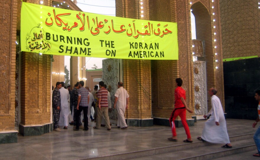 A banner bearing writing in English and Arabic reads: "Burning the Koraan — Shame on American." It was on display Friday at a mosque as Iraqis arrived for morning prayers.