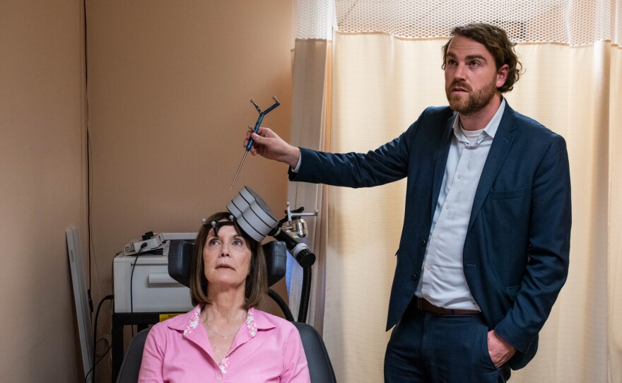Nolan Williams demonstrates the magnetic brain stimulation therapy he and his colleagues developed, on Deirdre Lehman, a participant in a previous study of the treatment.